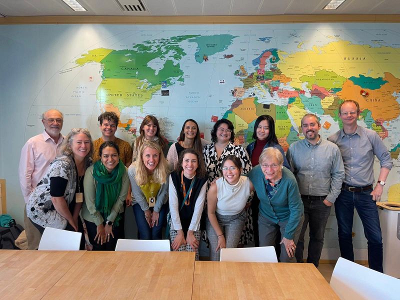 Group of people smiling for camera in front of world map