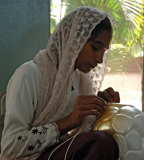 photo of woman hand-stitching a soccer ball